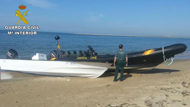Un agente junto a una narcolancha en una playa de Huelva