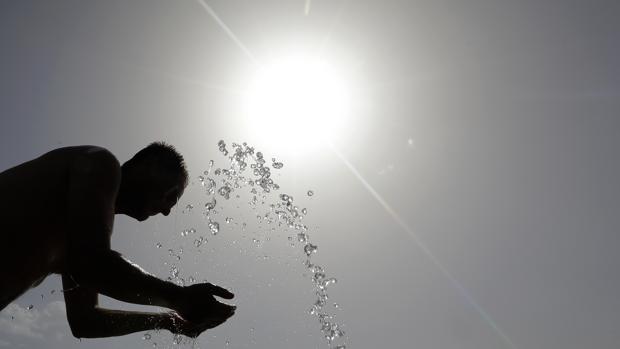 Un hombre se refresca en una fuente en plena ola de calor