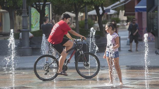 Una niña se refresca en la fuente de la plaza de las Tendillas