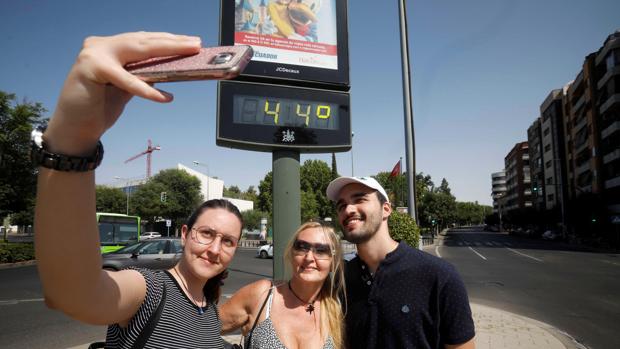 Unos turistas se fotografían con un termómetro del centro de Córdoba que indica 44 grados