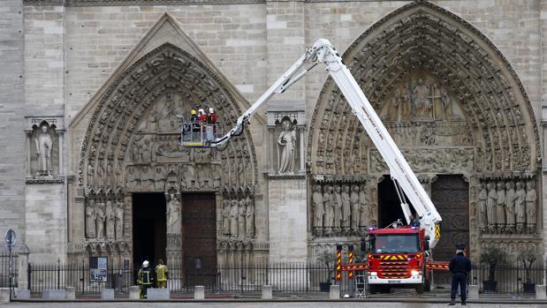 Varios bomberos trabajan en un elevador a la fachada de catedral de Notre Dame, este martes en París (Francia)