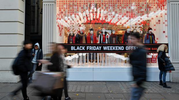 Fotografía de archivo de peatones pasando junto a los escaparates de tiendas que exponen sus descuentos por el Black Friday