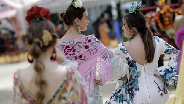 Unas jóvenes vestidas de flamenca pasean por el real